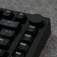 Close-up of a black MonsGeek M1 V5 HE Magnetic Keyboard with focus on keys like 'Home' and 'PgUp' on a textured surface.